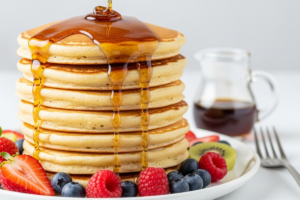 Pilha de panquecas americanas fofas com xarope de bordo e frutas frescas em prato branco, receita de panqueca, café da manhã, brunch, panqueca fofa, doce caseiro