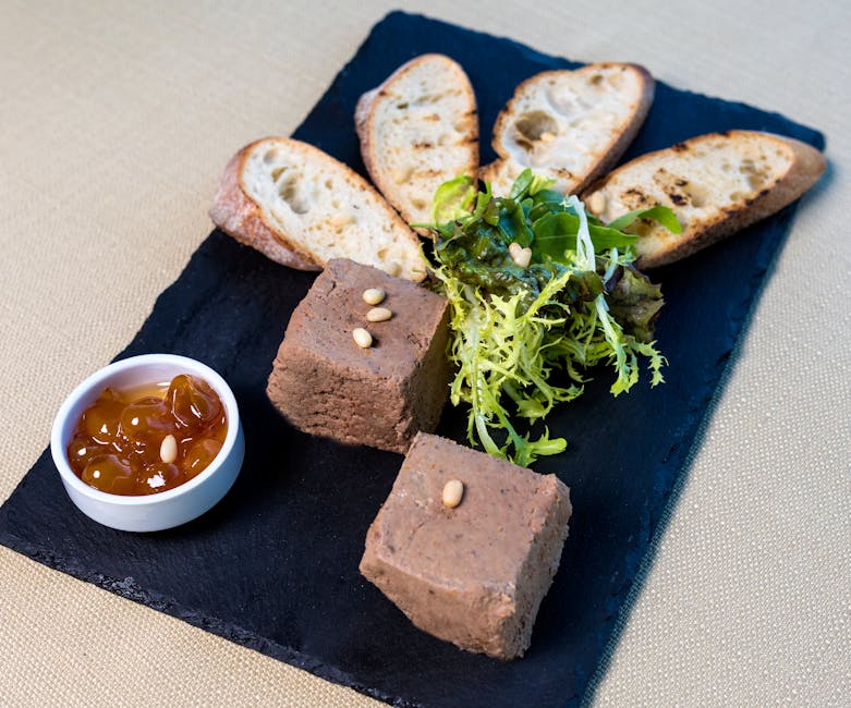 Delicious liver pâté with toasted baguette, salad, and chutney on a slate serving board.