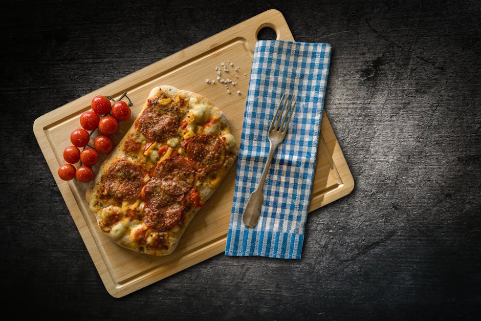 Delicious flatbread pizza topped with salami and herbs, paired with fresh cherry tomatoes on a wooden board.