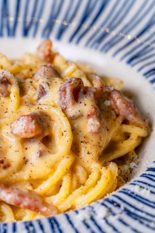Close-up do carbonara cremoso servido em cerâmica branca com pimenta-do-reino